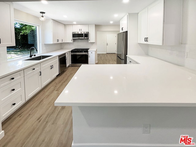 kitchen with sink, decorative backsplash, appliances with stainless steel finishes, light hardwood / wood-style floors, and white cabinetry