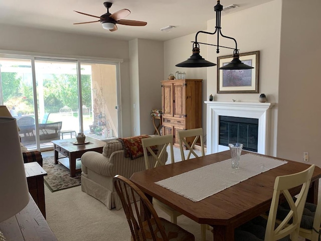 dining space featuring ceiling fan and light carpet