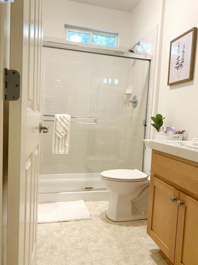 bathroom with tile patterned flooring, vanity, toilet, and an enclosed shower