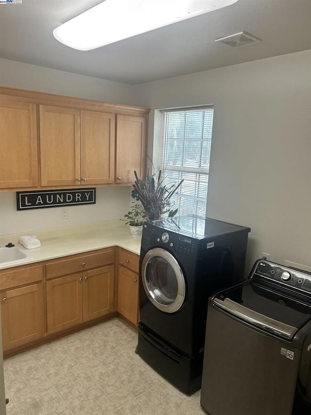 washroom with cabinets, sink, and washing machine and clothes dryer