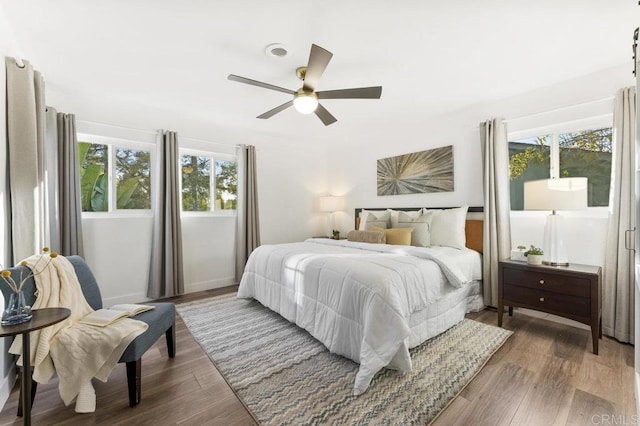 bedroom with ceiling fan, visible vents, and wood finished floors