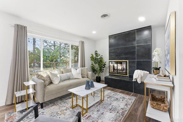 living room with a fireplace, visible vents, wood finished floors, and recessed lighting