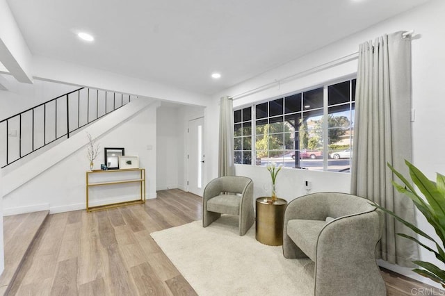 living area featuring baseboards, stairway, wood finished floors, and recessed lighting