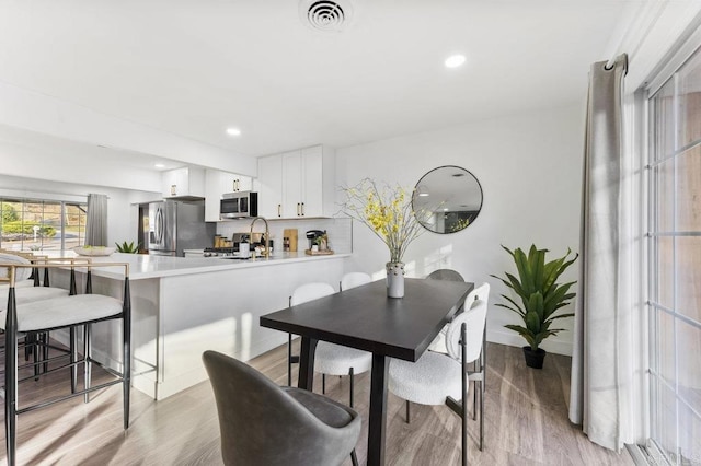 dining area with light wood-type flooring, visible vents, and recessed lighting