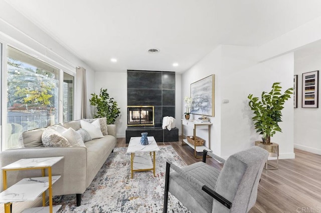 living room featuring recessed lighting, baseboards, wood finished floors, and a tile fireplace