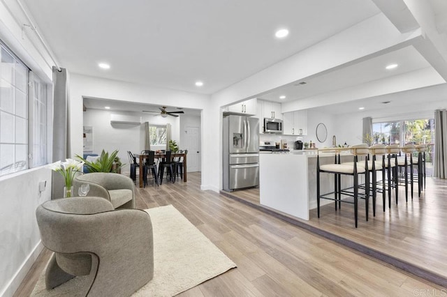 kitchen with appliances with stainless steel finishes, a breakfast bar, white cabinetry, and light wood-style flooring