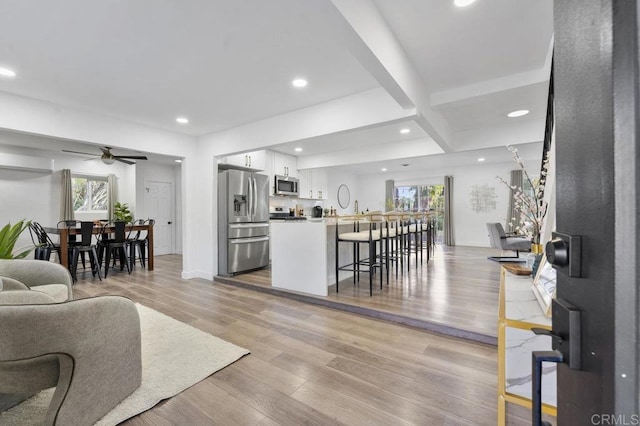 living room featuring a wealth of natural light, beam ceiling, light wood-style flooring, and recessed lighting