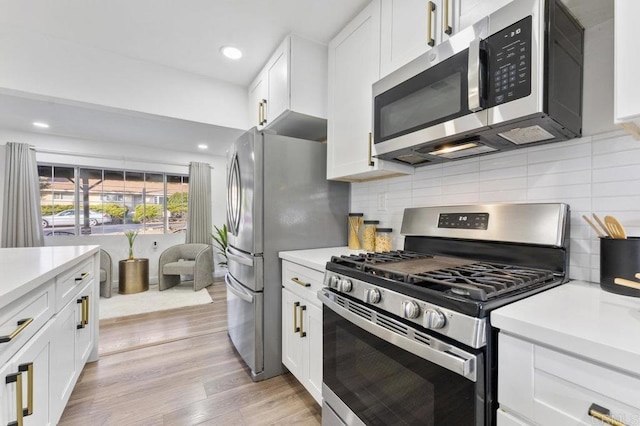 kitchen with white cabinets, light wood finished floors, stainless steel appliances, and light countertops