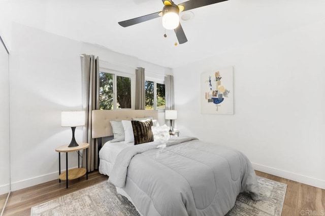 bedroom with ceiling fan, baseboards, and wood finished floors