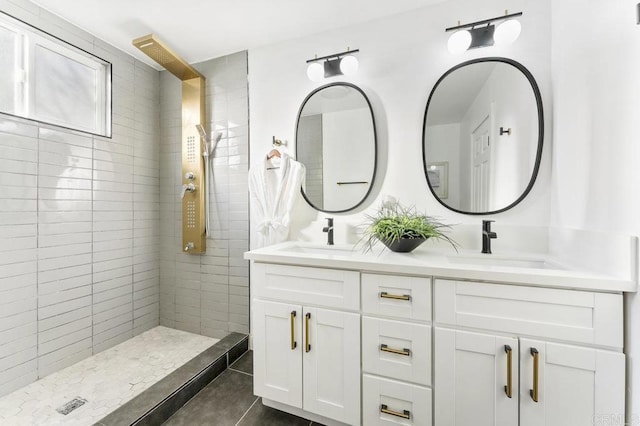 bathroom with tiled shower, double vanity, and tile patterned floors