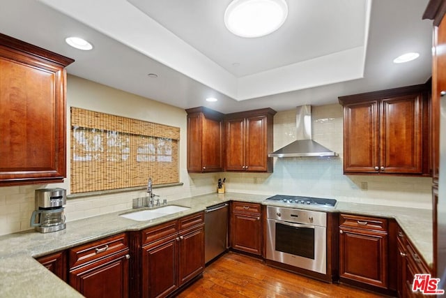 kitchen with tasteful backsplash, stainless steel appliances, dark wood-type flooring, sink, and wall chimney range hood