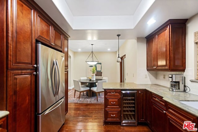 kitchen featuring pendant lighting, dark wood-type flooring, stainless steel fridge, light stone countertops, and beverage cooler