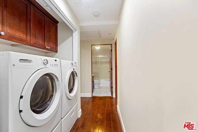 clothes washing area featuring cabinets, washer and dryer, and dark wood-type flooring