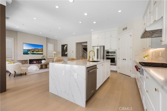 kitchen featuring white cabinetry, a center island with sink, stainless steel appliances, and light hardwood / wood-style flooring