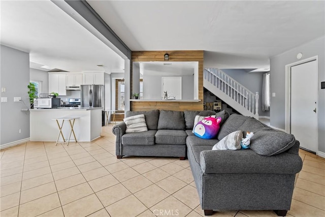 living room with stairway, baseboards, and light tile patterned floors