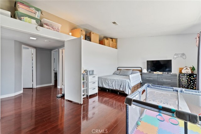 bedroom with visible vents, dark wood finished floors, and baseboards