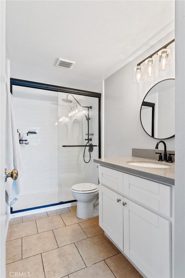 bathroom with toilet, vanity, visible vents, tile patterned floors, and a stall shower