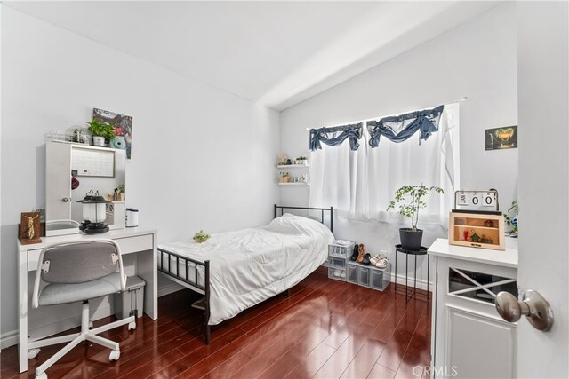 bedroom featuring lofted ceiling, baseboards, and dark wood finished floors