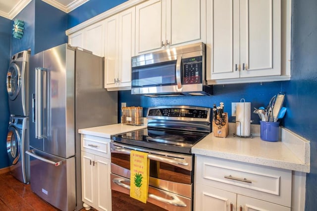 kitchen featuring white cabinets, stacked washer and dryer, ornamental molding, dark hardwood / wood-style flooring, and stainless steel appliances