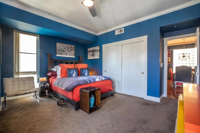 carpeted bedroom with a closet, ceiling fan, and crown molding