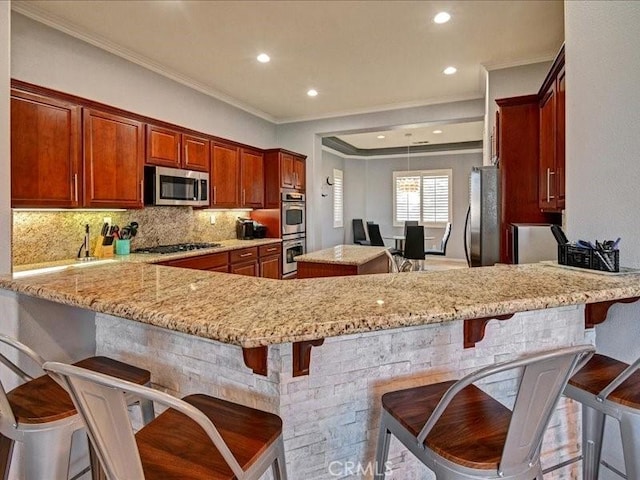 kitchen featuring a breakfast bar, tasteful backsplash, ornamental molding, kitchen peninsula, and stainless steel appliances