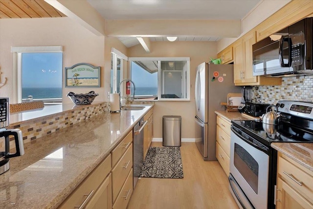 kitchen with tasteful backsplash, appliances with stainless steel finishes, light wood-type flooring, beamed ceiling, and a water view