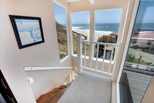 doorway to outside featuring carpet, a water view, and a beach view