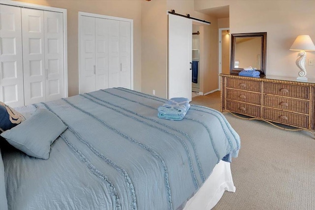 carpeted bedroom featuring a barn door and multiple closets