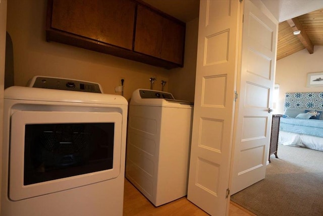 clothes washing area with wood ceiling, washing machine and dryer, cabinets, and light hardwood / wood-style floors