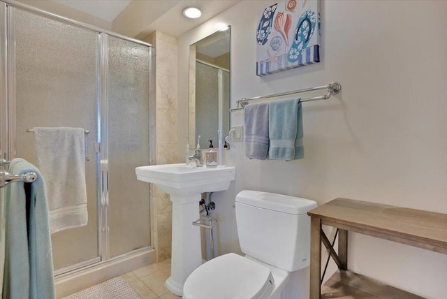 bathroom featuring toilet, tile patterned floors, and a shower with shower door