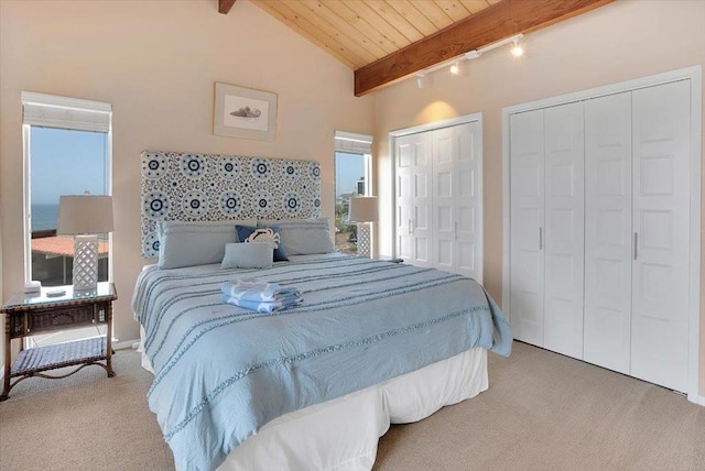 carpeted bedroom with lofted ceiling with beams, two closets, and wooden ceiling