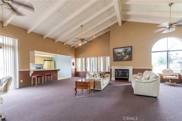 carpeted living room with beamed ceiling, ceiling fan, and high vaulted ceiling