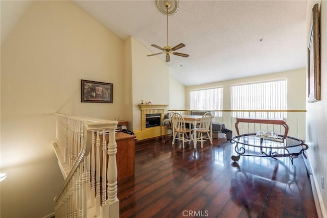 dining space with ceiling fan, lofted ceiling, dark hardwood / wood-style floors, and a brick fireplace