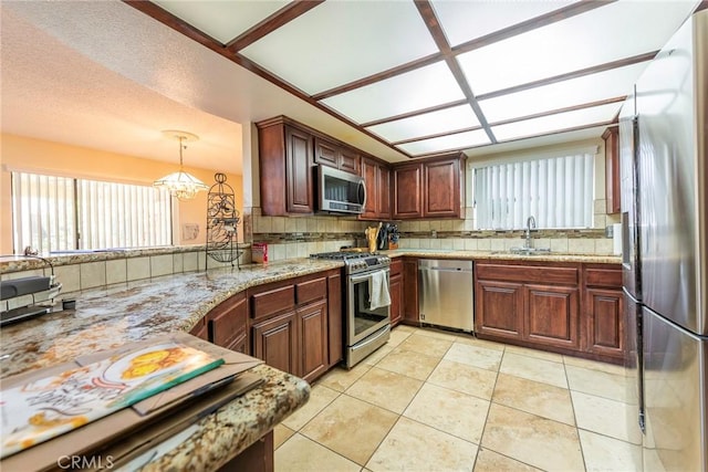 kitchen with light tile patterned flooring, sink, stainless steel appliances, light stone countertops, and backsplash