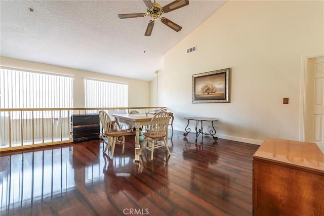 dining room featuring ceiling fan, dark wood-type flooring, a textured ceiling, and high vaulted ceiling