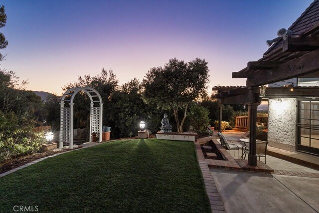 yard at dusk featuring a pergola and a patio area