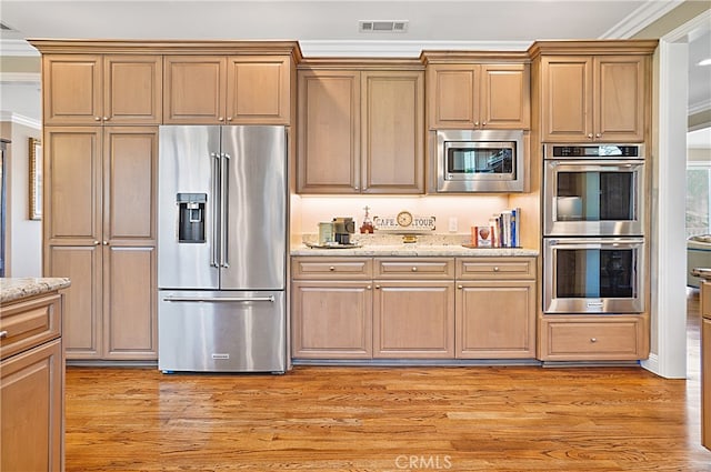 kitchen featuring light stone countertops, stainless steel appliances, ornamental molding, and light wood-type flooring