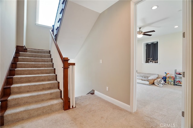 stairway featuring lofted ceiling, carpet flooring, and ceiling fan