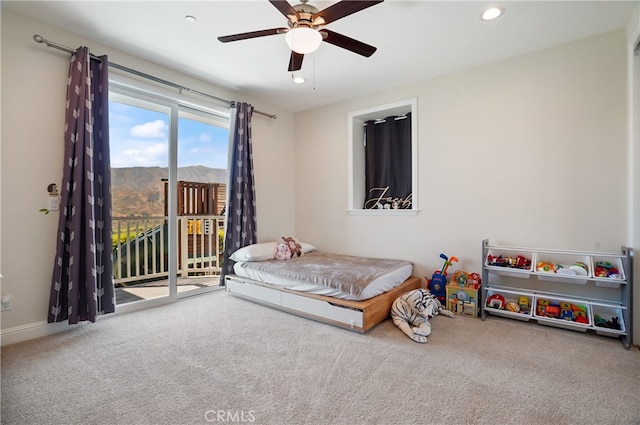 carpeted bedroom with a mountain view, access to exterior, and ceiling fan