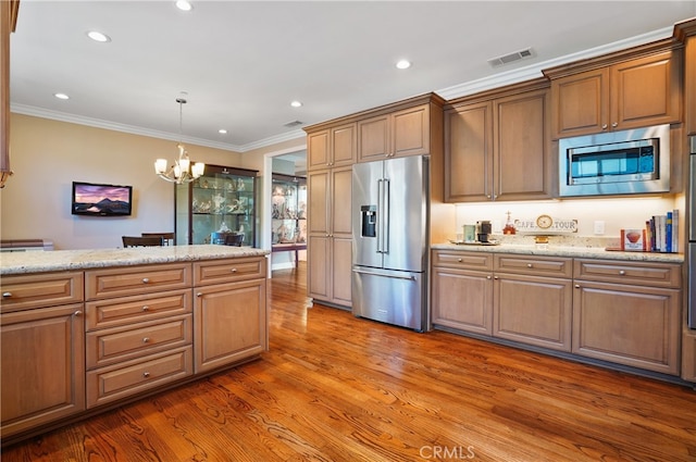 kitchen featuring hardwood / wood-style floors, light stone counters, an inviting chandelier, crown molding, and stainless steel appliances