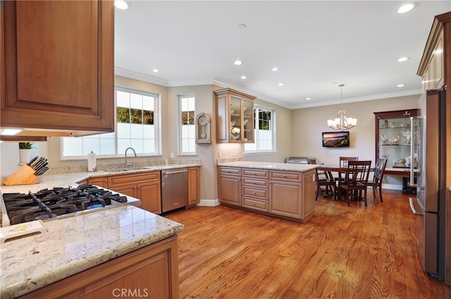 kitchen with kitchen peninsula, hanging light fixtures, light wood-type flooring, stainless steel appliances, and sink