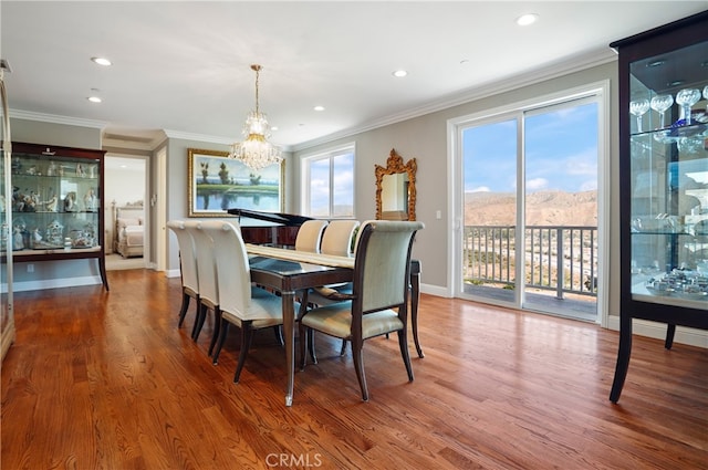 dining room with a mountain view, crown molding, an inviting chandelier, and hardwood / wood-style floors