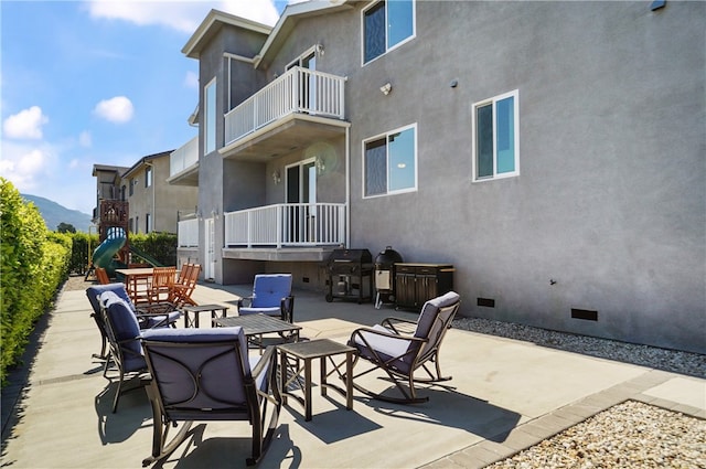 view of patio featuring a balcony, a mountain view, and a playground