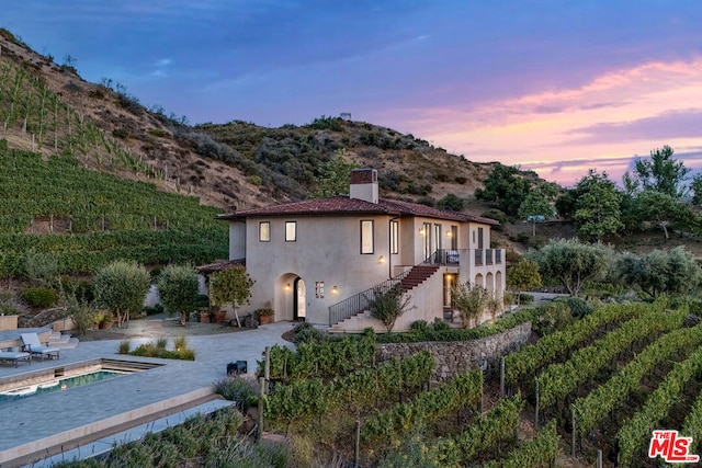 property exterior at dusk with a mountain view and a patio