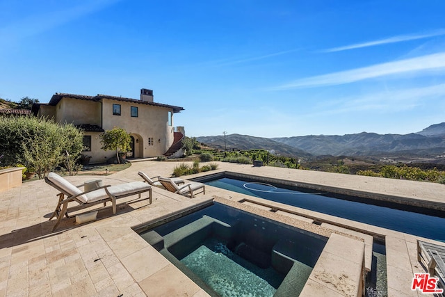 view of swimming pool with a mountain view, an in ground hot tub, and a patio