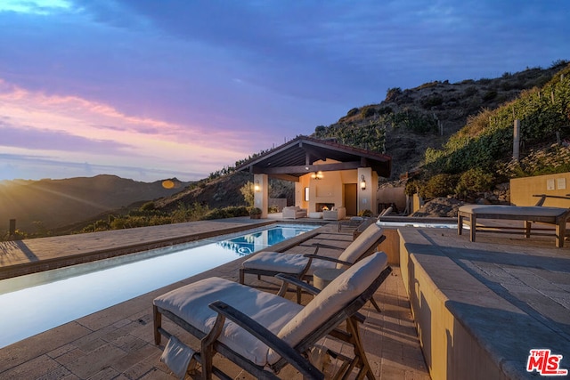 pool at dusk with a mountain view and a patio