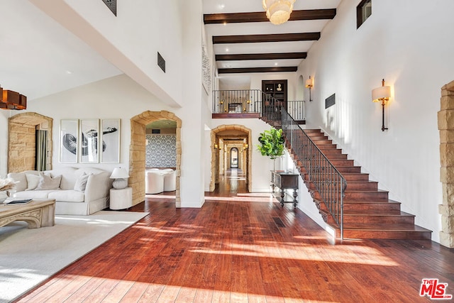 entrance foyer featuring beam ceiling, a towering ceiling, and hardwood / wood-style floors