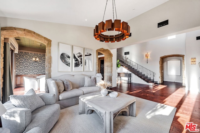 living room featuring high vaulted ceiling, a notable chandelier, and hardwood / wood-style floors