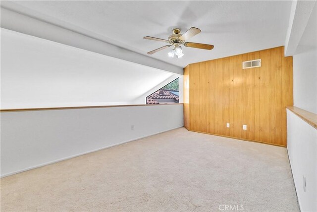 bonus room featuring wood walls, light carpet, ceiling fan, and vaulted ceiling