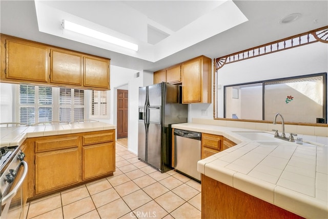 kitchen featuring sink, stainless steel appliances, tile counters, and light tile patterned flooring